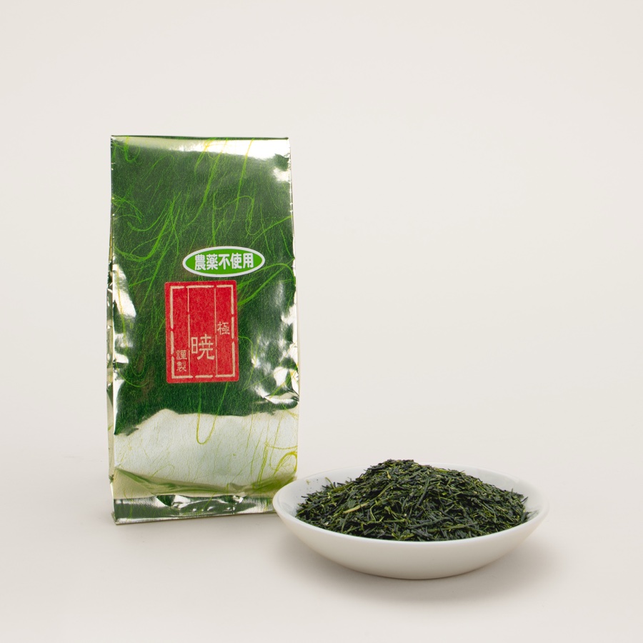 A foil bag of sencha beside a small dish of loose leaf tea, on a plain background